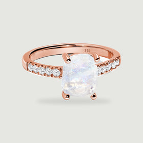 A rose gold vermeil ring presents a raw milky moonstone with blue reflections and bright stones along its band.