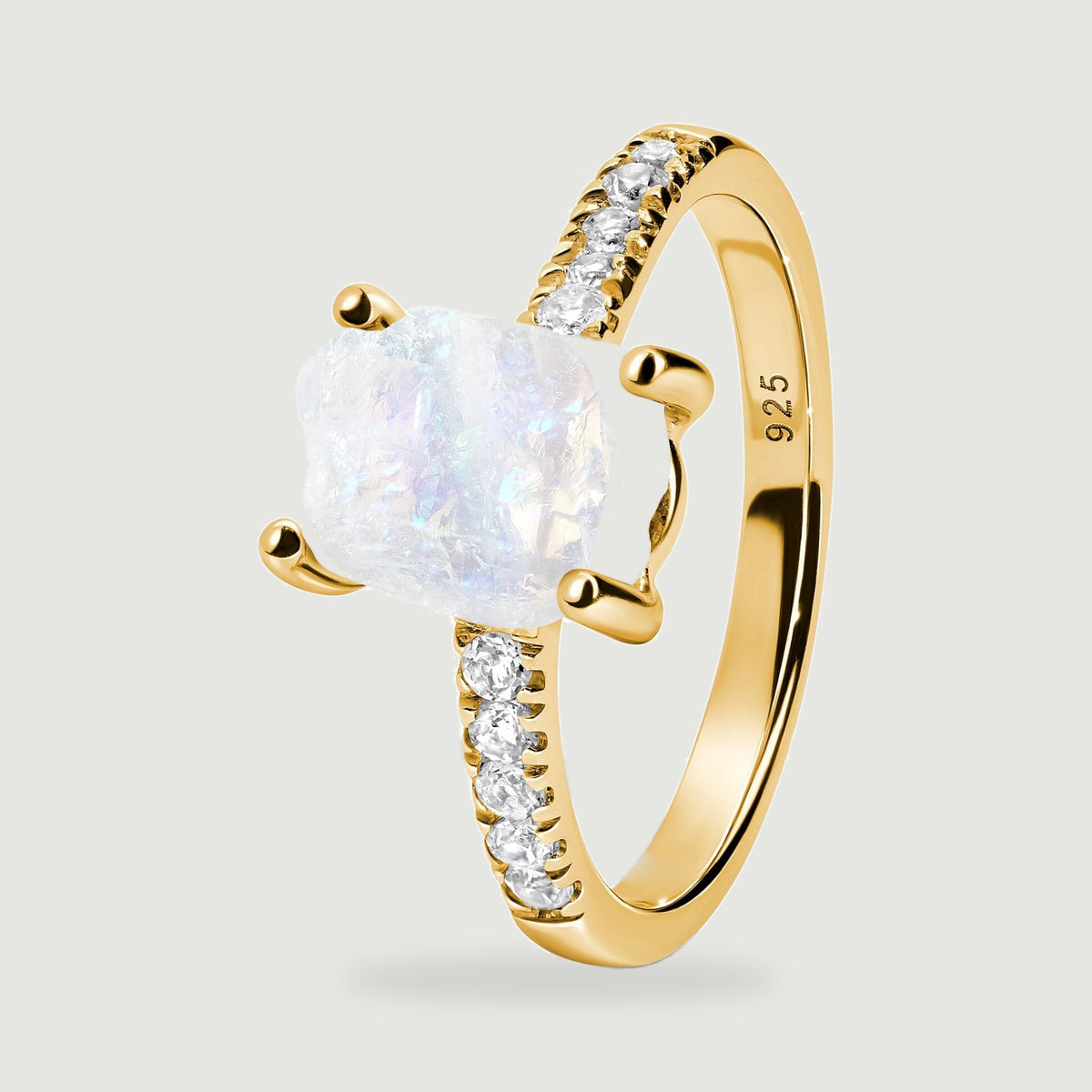 The side of a yellow gold vermeil ring shows rounded prongs, a rough translucent moonstone, and a polished inner band.