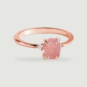 A rose gold vermeil ring with a raw pink center stone is shown from an elevated front angle.