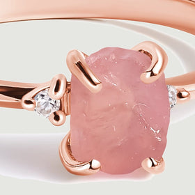 Rose gold prongs curve around the textured pink stone beside a small round clear stone.