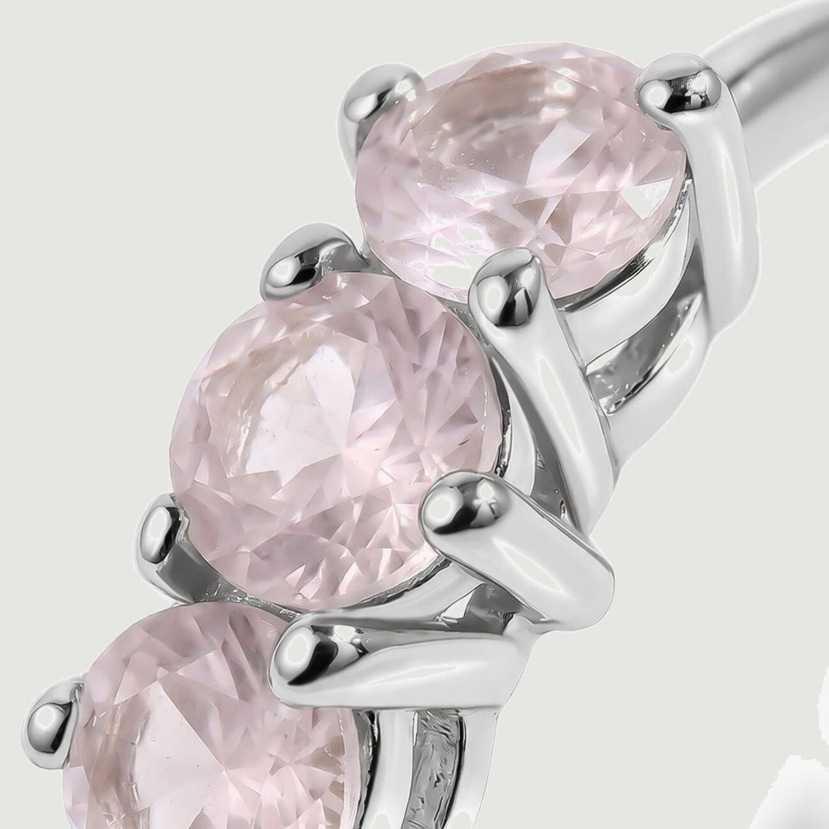A close view shows faceted pale pink stones held by polished silver-tone prongs.