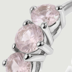 A close view shows faceted pale pink stones held by polished silver-tone prongs.