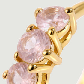A close view shows faceted pale pink stones held by polished yellow-gold-tone prongs.