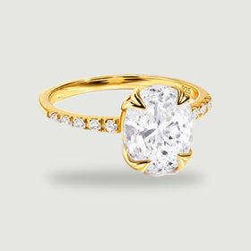 A complete yellow gold vermeil ring with an oval clear faceted stone and small stones along the shoulders rests on a light gray background.