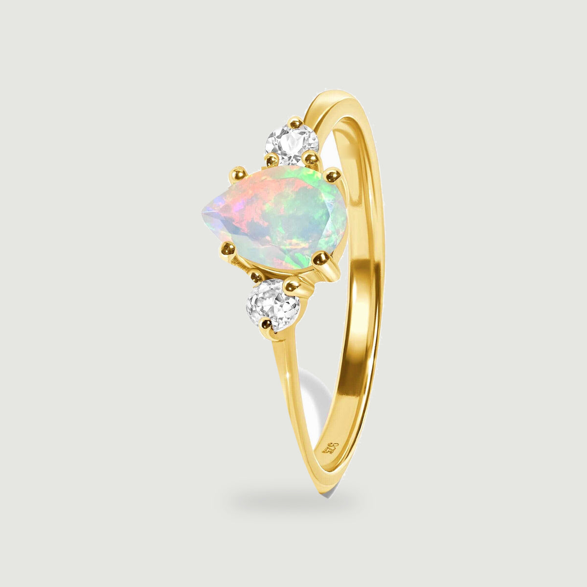 An upright yellow gold ring reveals its slim band, raised opal setting and round side stones.