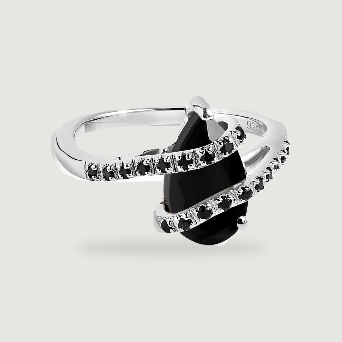 A polished silver ring with a pear-shaped black stone and two curved rows of small black stones rests on light gray.