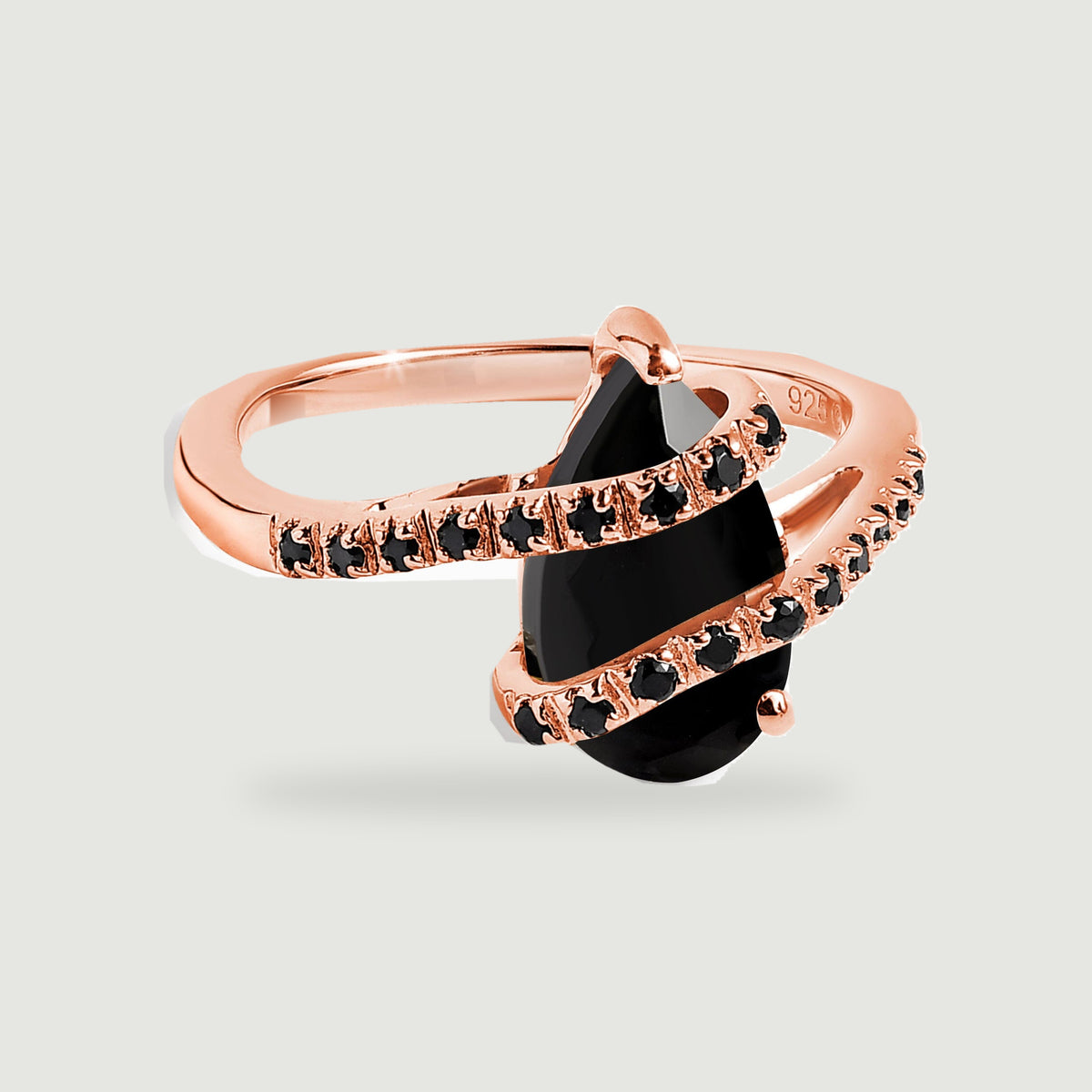 A rose gold ring shows a faceted black pear-shaped stone crossed by two narrow stone-set bands.