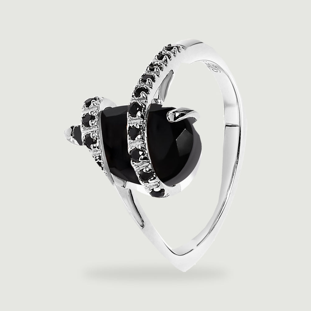 An angled silver ring reveals the raised black stone, supporting prongs, and curved band.