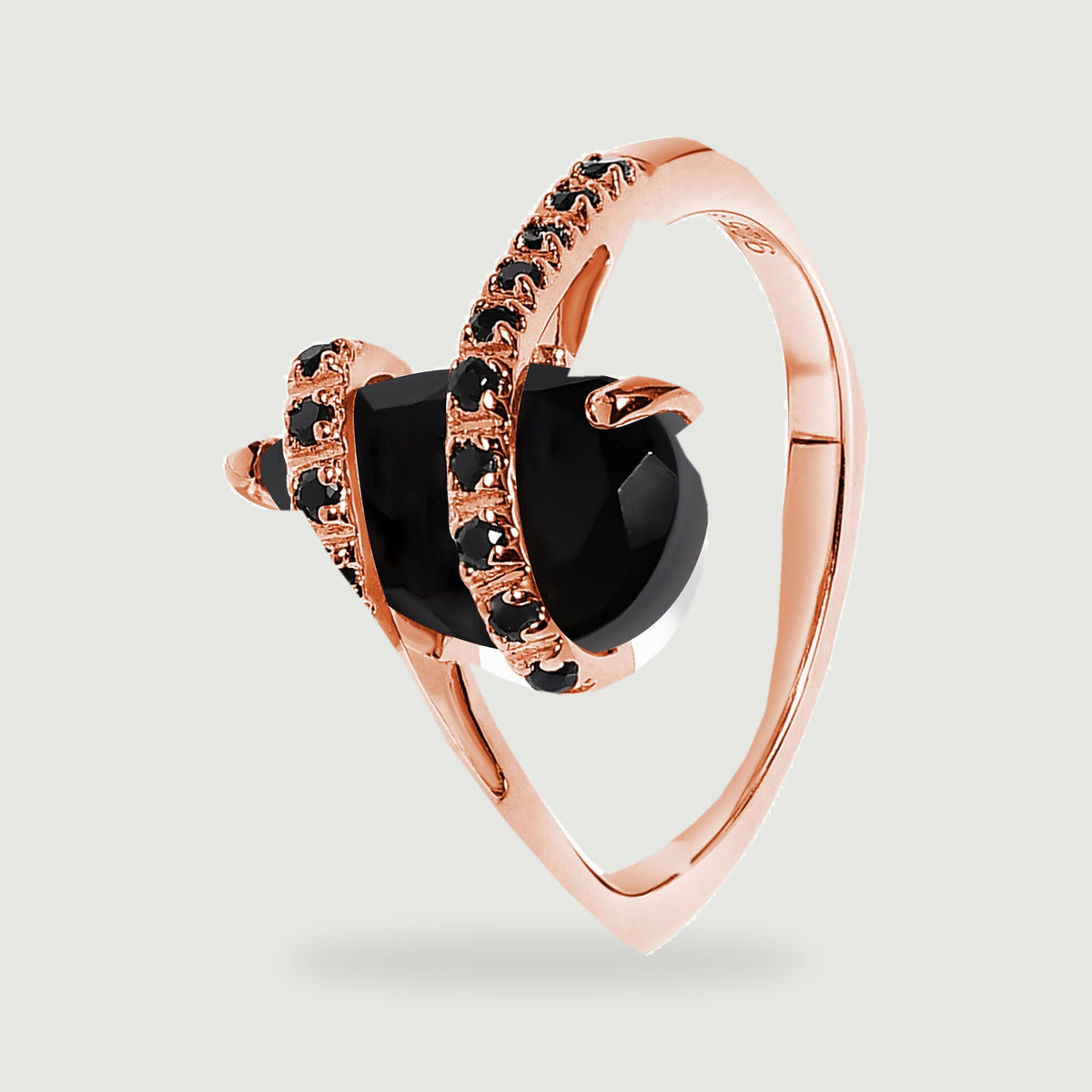 The rose gold ring is viewed from the side with the round band and black stone setting visible.