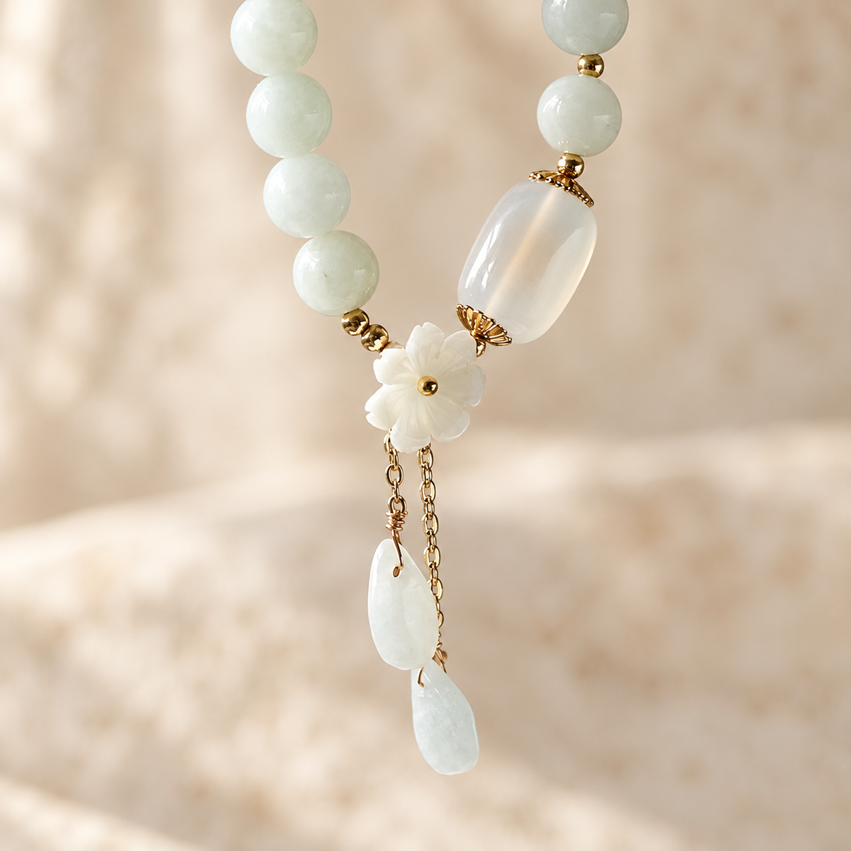Close-up of the bracelet's white flower, oval bead, and two hanging stone drops.