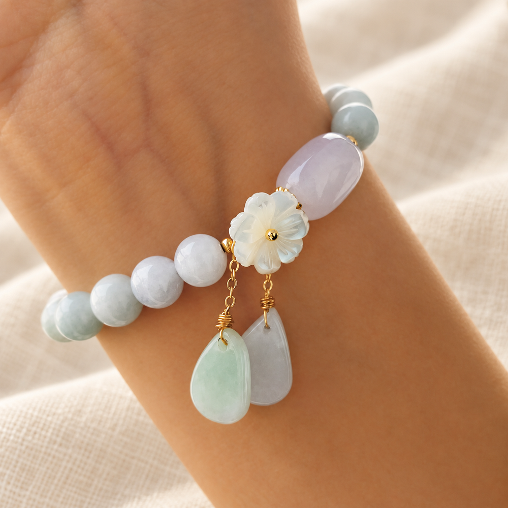 White jade bead bracelet worn on a wrist, with two stone drops hanging below the flower.