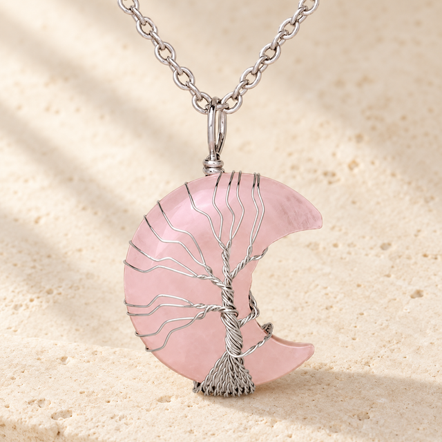 Pale pink crescent pendant with a silver-toned wire tree and chain.