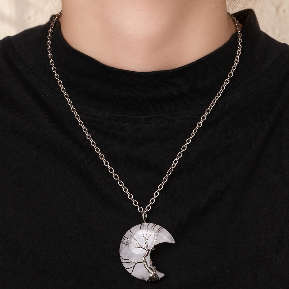 White crescent tree pendant worn on a silver-toned chain over a black top.