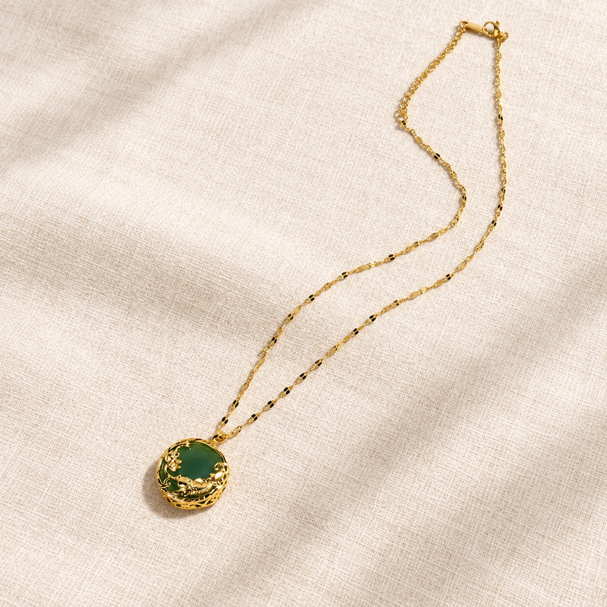 Green koi and lotus pendant with its full gold-toned chain laid flat.