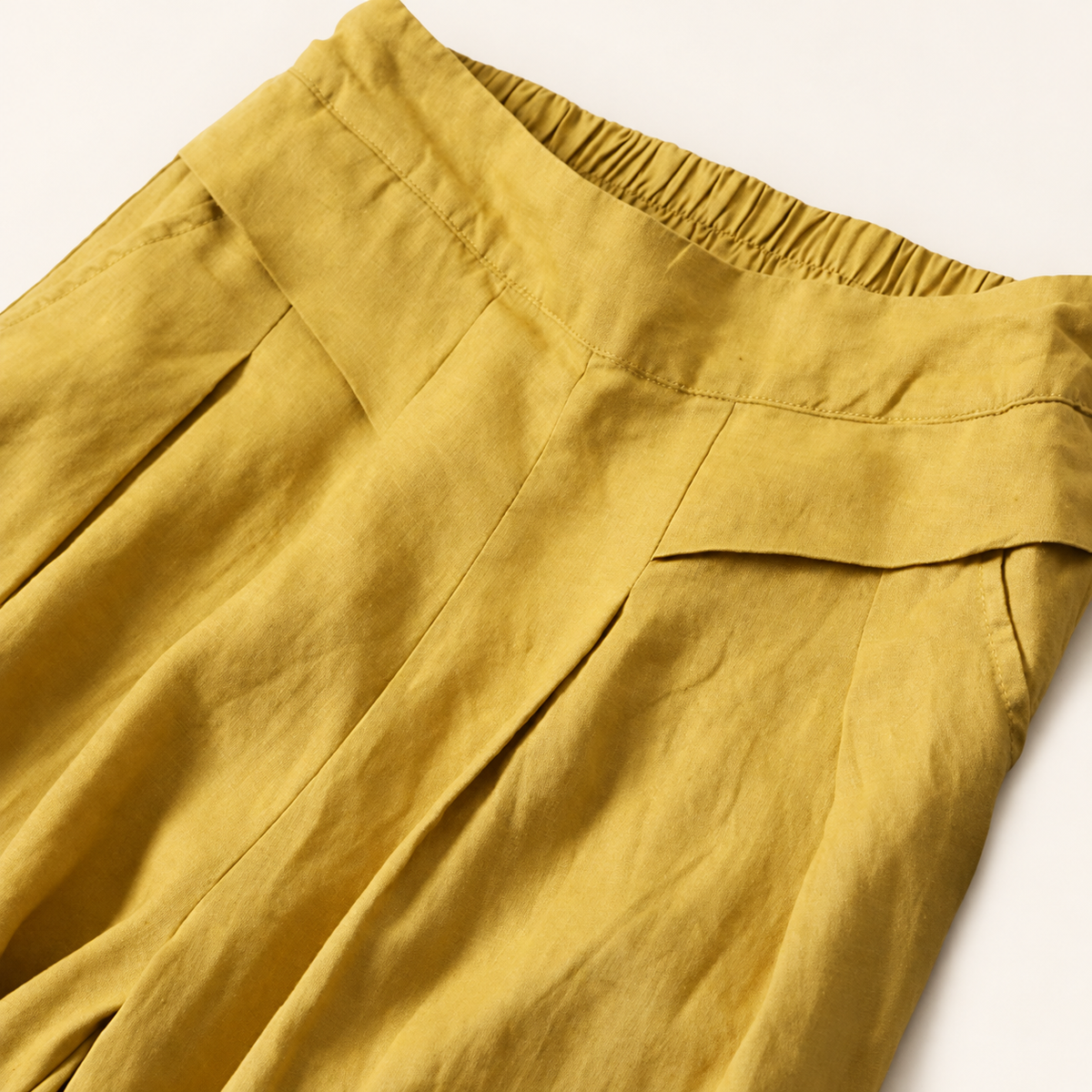 Ease pants in Yellow, close-up of the waistband and front pleats.