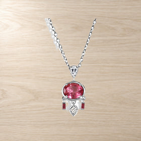 Pink topaz pendant with white zircon accents on a warm wooden table