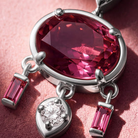 Close-up of an oval pink topaz pendant with pink baguette stones beside it