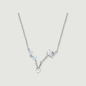 A silver necklace has four round pale stones and small clear accents connected in a V-shaped setting on a light gray background.
