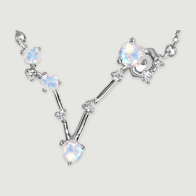 A close view shows the silver prongs, four round iridescent stones and tiny clear accents along the angular pendant.