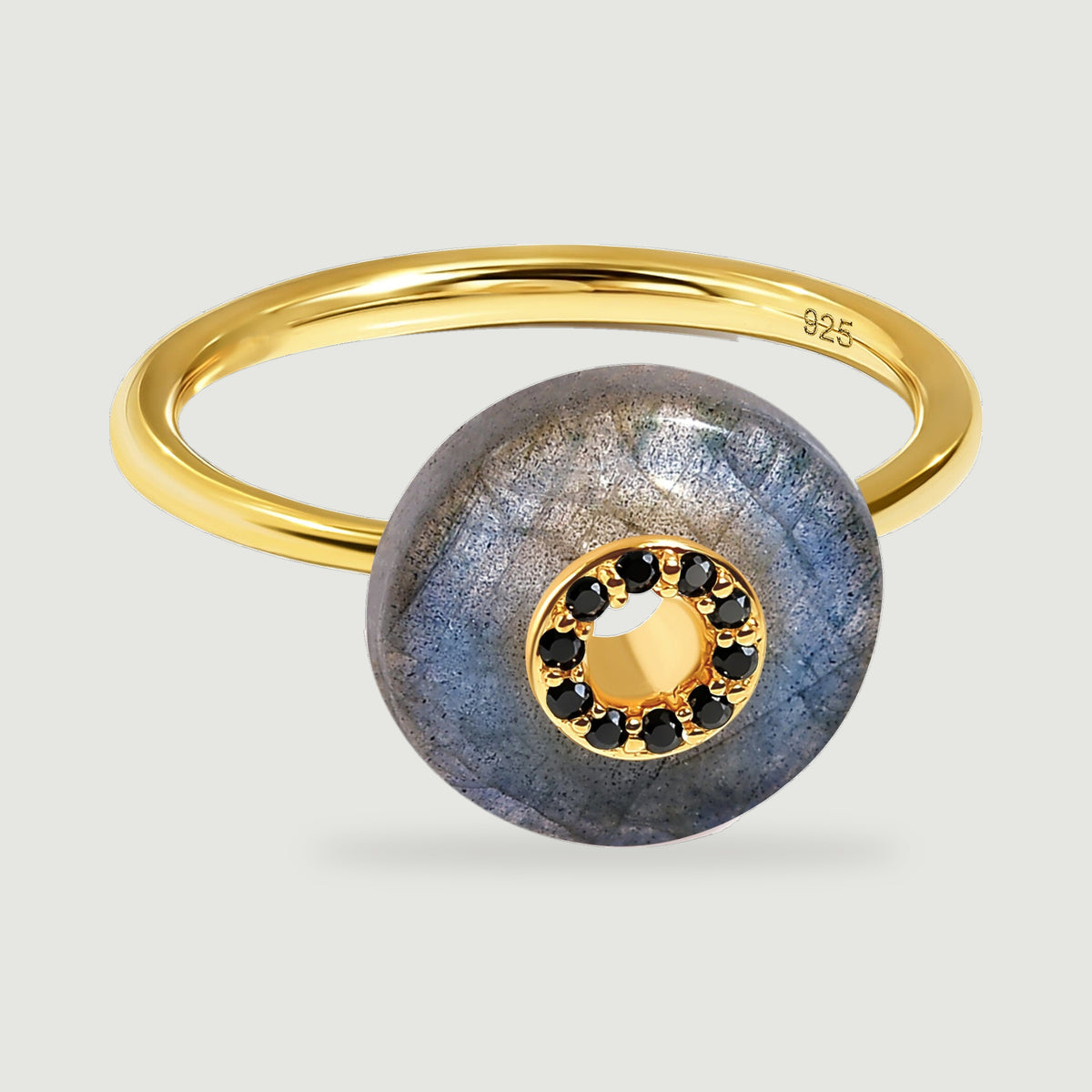 A yellow gold vermeil ring lies at an angle, revealing blue reflections in its labradorite disc and a row of black stones.
