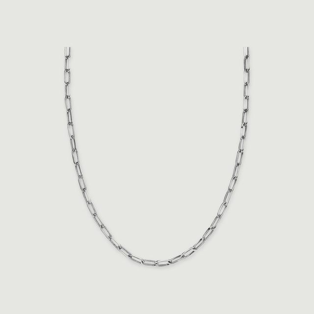 A silver tone necklace shows elongated open links on a light grey background.