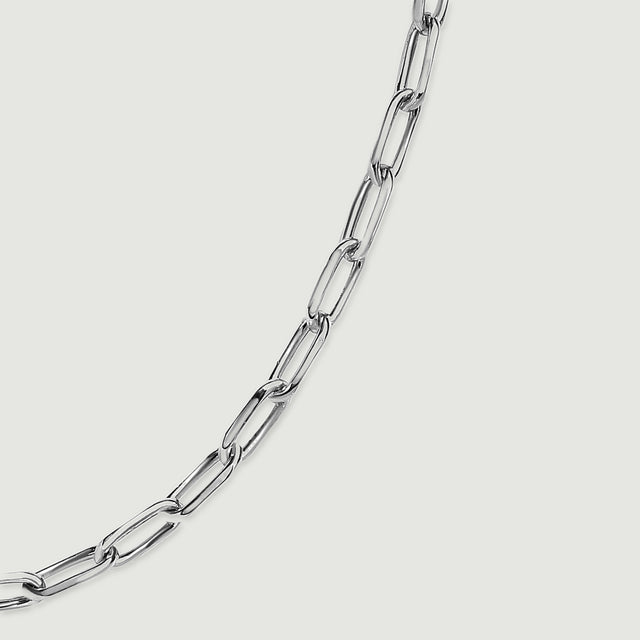Polished silver tone links curve diagonally across a clean light grey surface.