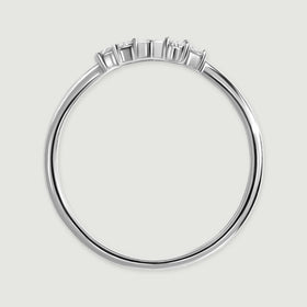 The white gold ring is viewed from the side, showing slender prongs above its polished band.