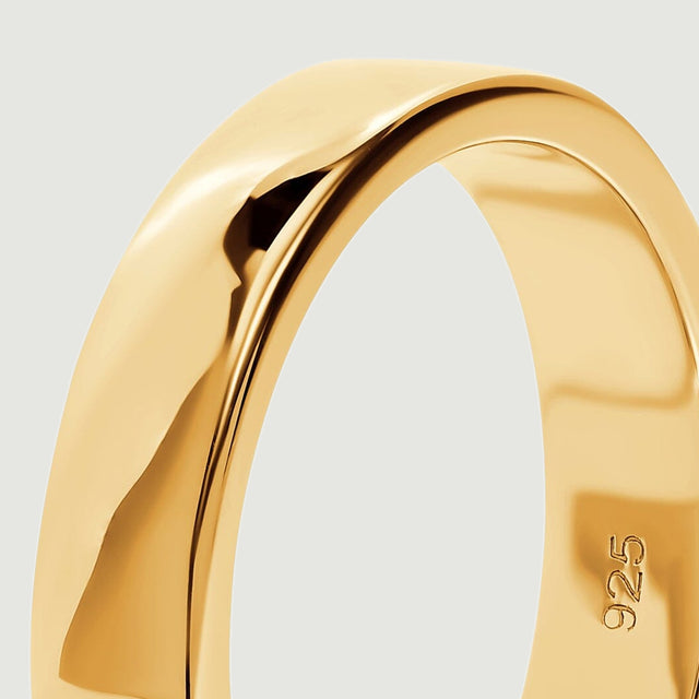 A close view shows the reflective outer wall and smooth edge of the yellow gold band.