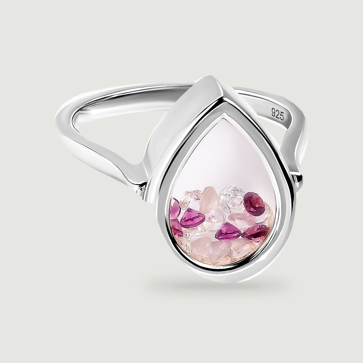 A polished sterling silver ring holds pale pink and deep raspberry stones inside a teardrop-shaped chamber on a light grey surface.