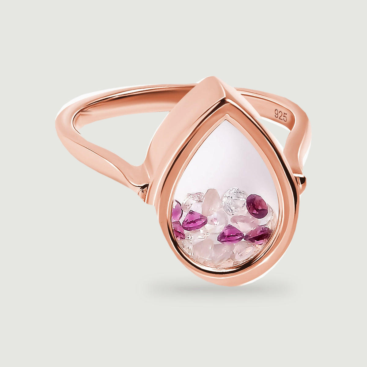 A rose gold vermeil ring is centered above a soft shadow with its pink and raspberry stones visible through the teardrop window.