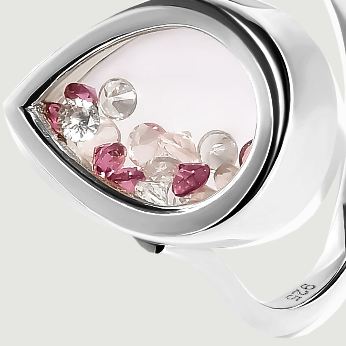 A close view of the silver teardrop setting reveals faceted pale pink, clear and raspberry stones behind its smooth window.