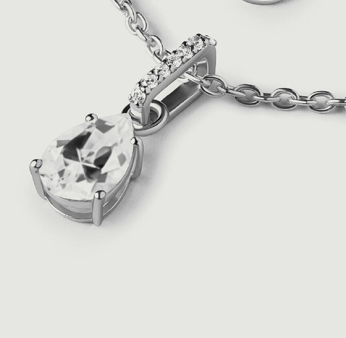 An oblique view of the silver pendant shows the pear-cut stone, curved bail, and raised side of the setting.