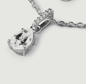 An oblique view of the silver pendant shows the pear-cut stone, curved bail, and raised side of the setting.