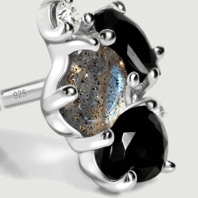 The side of a silver stud displays its open setting, blue stone reflections and a post bearing a 925 mark.