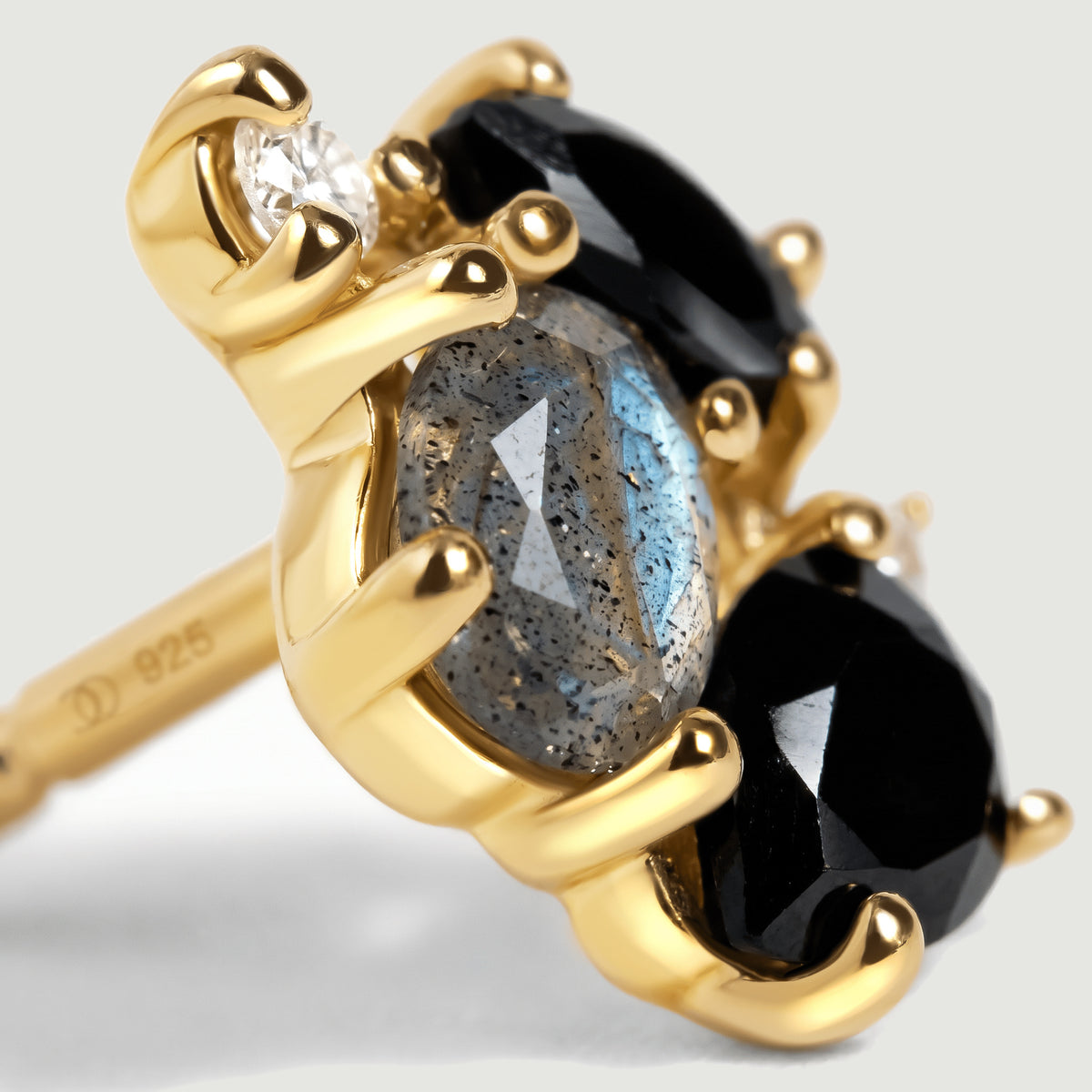 An angled gold vermeil stud shows an oval labradorite between two black stones with clear round accents.