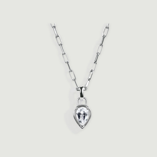 A silver-tone necklace with elongated links and a clear pear-shaped pendant is centered on a light gray surface.
