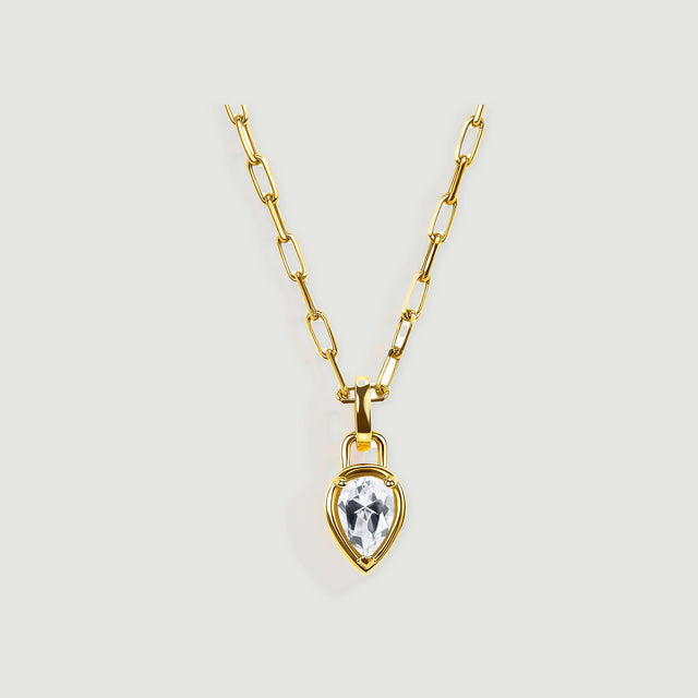 A yellow-gold-tone necklace with an elongated-link chain and a clear teardrop pendant rests against a pale gray background.