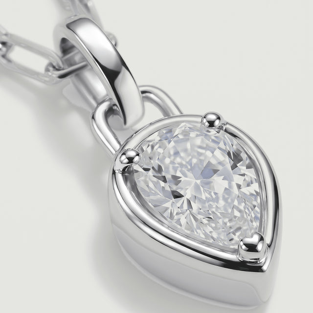 A close view shows the clear faceted stone, three silver-tone prongs, and the polished pendant loop.