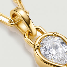 The polished yellow-gold-tone bail and rounded prongs frame a close-up of the clear faceted stone.