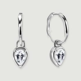 A pair of silver-toned hoop earrings with pear-shaped clear stones rests on a light gray background.