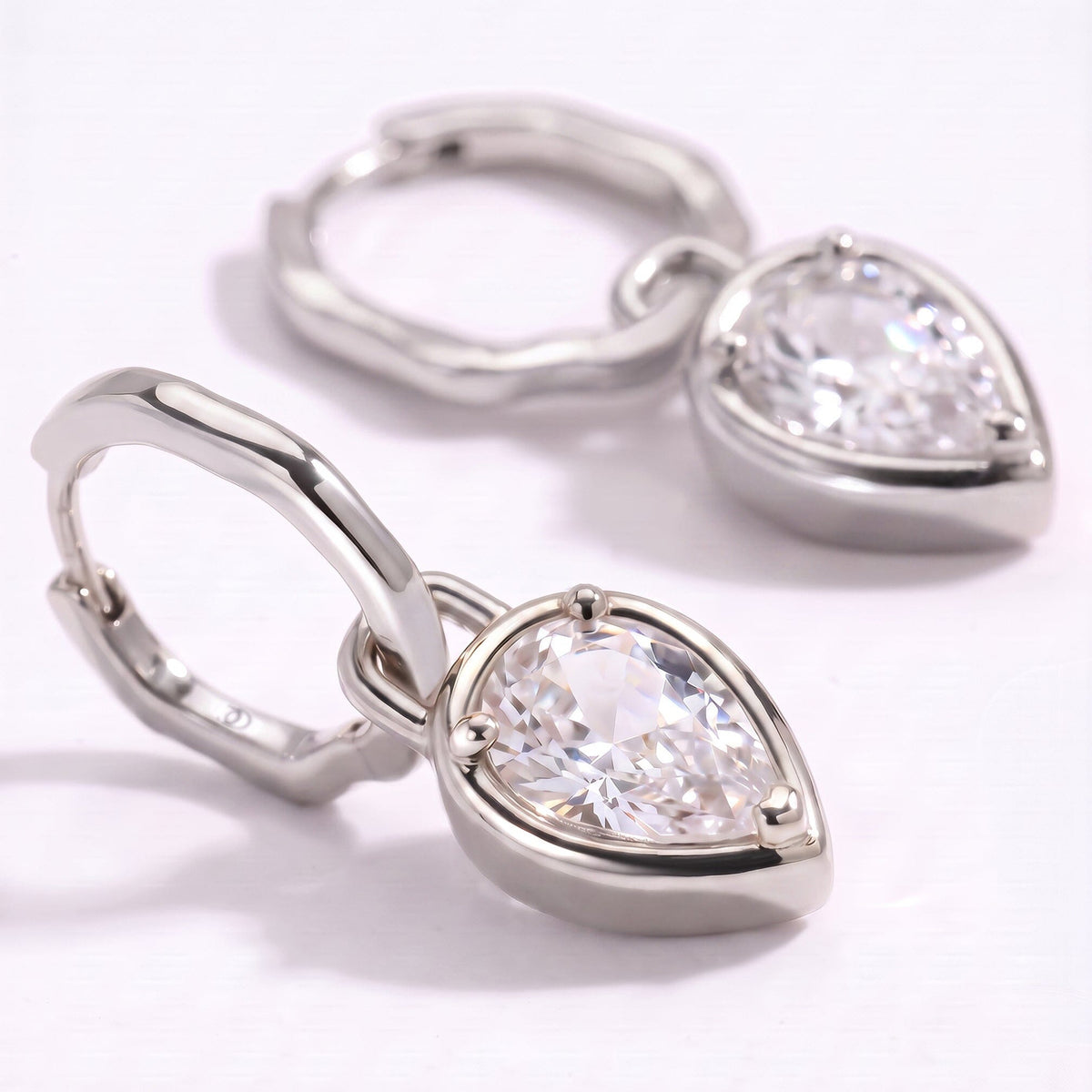 A close view shows the faceted clear stone, three prongs, and polished silver-toned hoop.