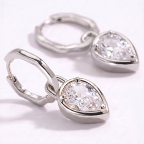 A close view shows the faceted clear stone, three prongs, and polished silver-toned hoop.