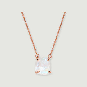 A raw white moonstone pendant with four rose gold prongs hangs from a fine link chain on a pale grey background.