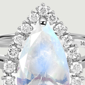 A close view reveals the pointed moonstone tip, polished prongs, and round diamonds along the upper halo.