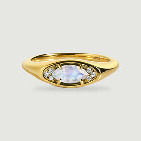 A yellow gold ring displays an eye-shaped setting with a faceted moonstone and clear accent stones.