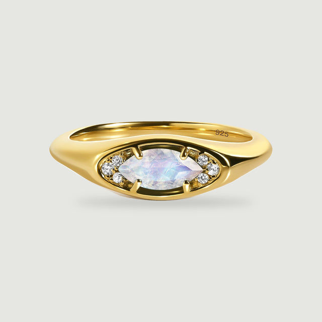 A yellow gold ring displays an eye-shaped setting with a faceted moonstone and clear accent stones.