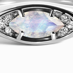 The front of the silver ring shows a pale marquise moonstone between bright clear stone clusters.