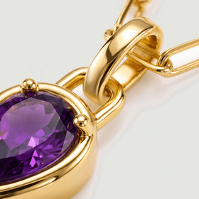 A close view reveals the purple gemstone facets, gold prongs and curved pendant bail.