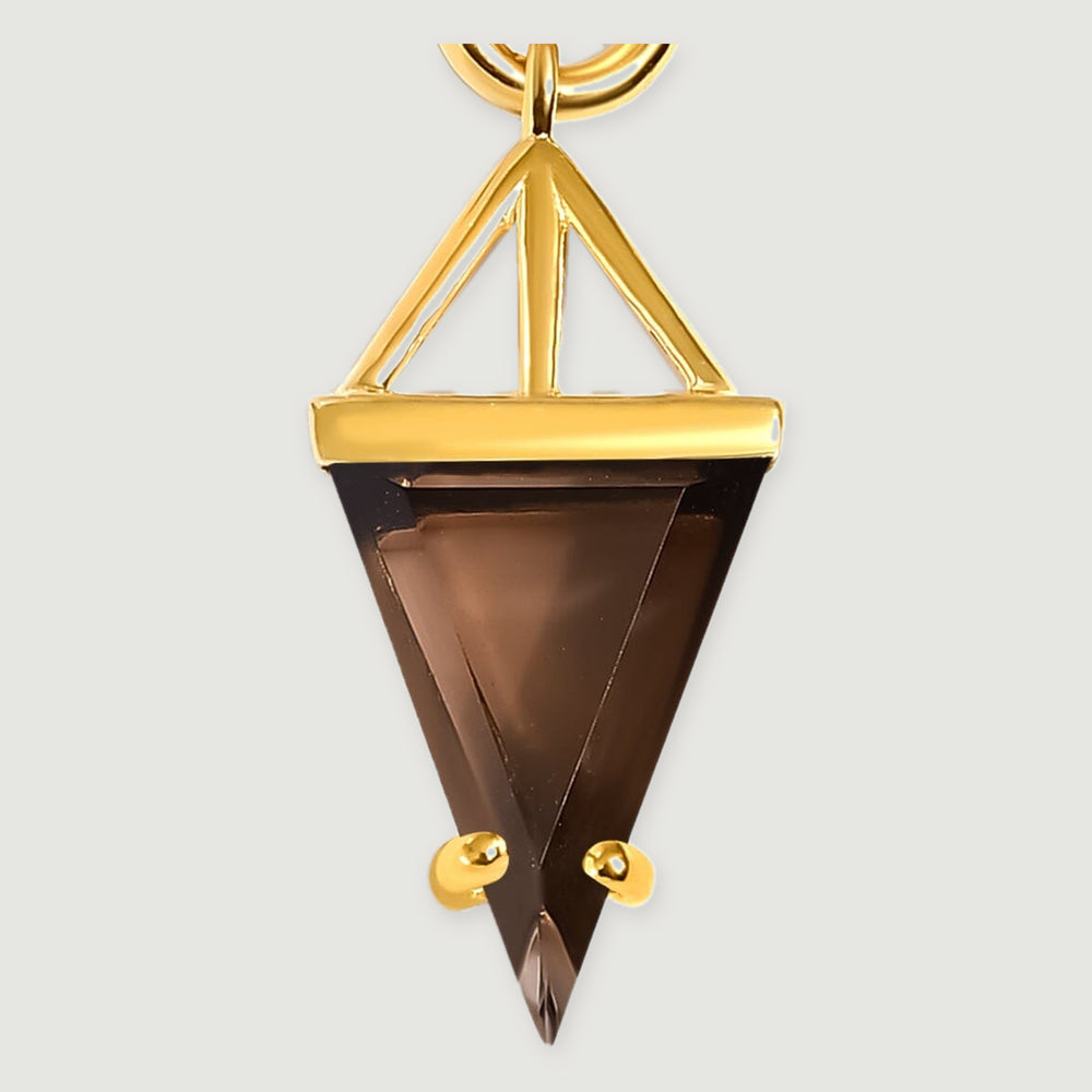 A close view shows the smoky quartz triangle, open gold support and two rounded gold prongs against a pale gray background.