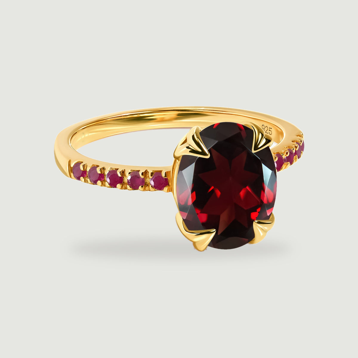A yellow gold vermeil ring with an oval deep red gemstone and round red stones along the band.